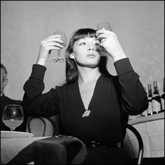 a woman sitting at a table with two wine glasses