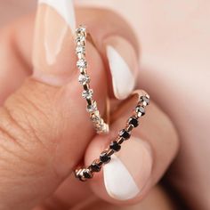 a woman's hand holding an open ring with black and white stones on it