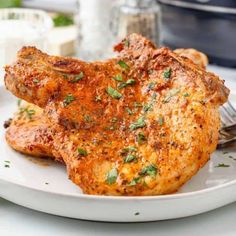 a white plate topped with meat covered in sauce and garnished with parsley