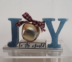 a metal apple sitting on top of a wooden block that says joy to the world