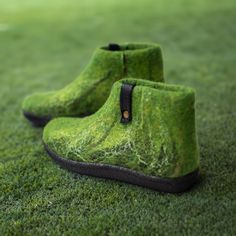 a pair of green boots sitting on top of a lush green field