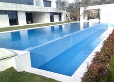 an empty swimming pool in the middle of a lawn area next to a large building