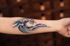 a person's arm with a tattoo on it that has a wave coming out of the water