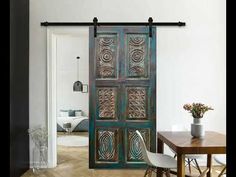 a room with a table, chairs and a large wooden door that has intricate designs on it