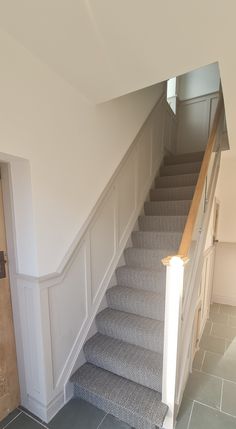 a staircase with carpeted steps leading up to the second floor and another door in the background