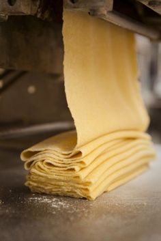 a stack of uncooked pasta sitting on top of a metal table next to a machine