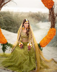 a woman in a green and yellow wedding dress with flowers on the ground next to her