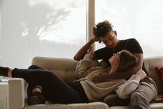 two people sitting on a couch with their arms around each other