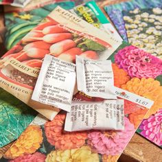 several packets of seeds sitting on top of each other next to some flowers and leaves