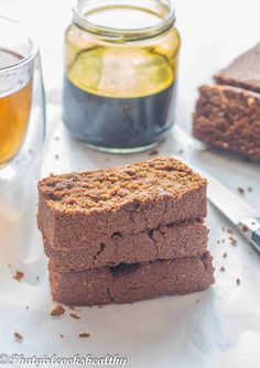 three pieces of brownie sitting on top of a white plate next to a glass of tea