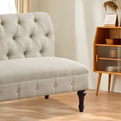 a white couch sitting on top of a wooden floor next to a book shelf and window