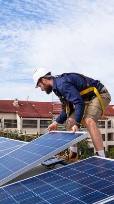 a man on top of a roof installing solar panels