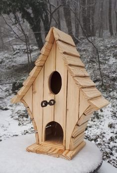 a wooden bird house sitting on top of snow covered ground