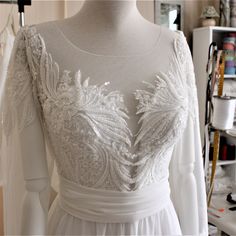 a white wedding dress on a mannequin in a room with sewing supplies and other items