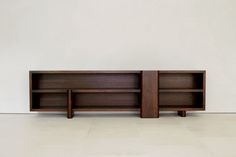 two wooden bookshelves sitting side by side against a white wall in an empty room