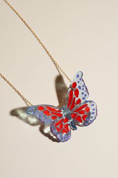 Based in: USAThis captivating piece is not just jewelry; it's a statement of individuality and elegance.Imagine a delicate butterfly, seemingly suspended in mid-flight, its wings adorned with mesmerizing red specks and intricate purple details. Each detail is meticulously crafted to capture the essence of grace and allure. This necklace is more than just an accessory; it's a reflection of your unique style and appreciation for sustainable craftsmanship. Wear it proudly to elevate any outfit, whether it's a casual ensemble or formal attire, and let it be a conversation starter wherever you go. Make a statement with this one-of-a-kind necklace! Details Made in: Broward, Florida Dimensions: 1.5" in. x 2" in. Chain length: 18" Weight: 0.1 oz. Metal: gold-plated chain Material: soy-based resin Whimsical Red Party Jewelry, Butterfly Charm Necklace For Party, Handmade Butterfly Necklace For Parties, Red Butterfly Jewelry For Gift, Handmade Unique Butterfly Necklace, Red Butterfly Necklace For Gift, Elegant Multicolor Butterfly Necklace As Gift, Handmade Unique Butterfly Shaped Necklace, Elegant Multicolor Butterfly Necklace Gift