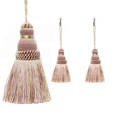 three tassels hanging from hooks on a white background, one is pink and the other is beige