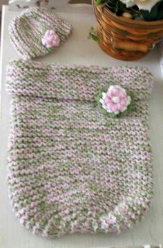 a crocheted bag and hat sitting on top of a table next to flowers