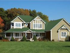 a large house with green roof and white windows