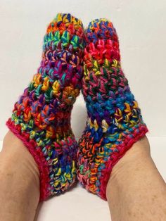 someone is wearing colorful crocheted slippers on their feet