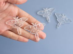 a hand holding three small plastic butterflies