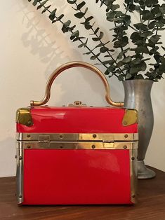 a red purse sitting on top of a table next to a vase filled with flowers