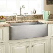 a stainless steel sink in a kitchen with granite counter tops and white cabinetry next to a window