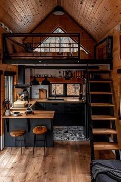 the interior of a tiny cabin with stairs leading up to it's loft bed