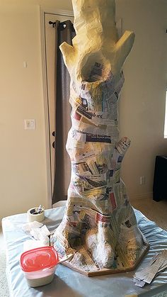 there is a very tall statue made out of newspapers on top of a sheet of paper