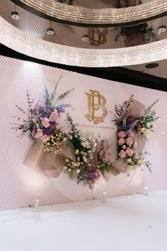 flowers are arranged on the side of a wall in front of a chandelier