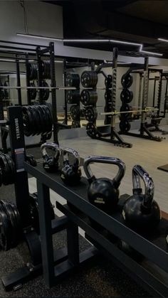 a gym filled with black kettles and exercise equipment on top of a wooden floor