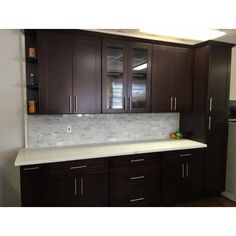 a kitchen with dark wood cabinets and white counter tops