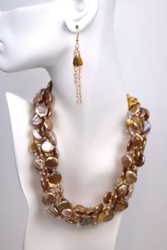 Gold Rush is a striking statement piece that demands attention. Seven strands of gold coin pearls with beaded chain and Swarovski© crystal. The gold adjustable chain allows you to adjust the length of the necklace, making it the perfect length for you. This style combines with any outfit to create an instant style update and can be worn to work or an evening on the town Shimmering and eye-catching, this necklace is the perfect statement piece for any occasion. Gold Multi-strand Pearl Necklace With Adjustable Chain, Gold Dangle Pearl Necklace For Party, Gold Pearl Lariat Chain Necklace, Elegant Gold Coin Necklace With Pearl Charm, Handmade Gold Multi-strand Pearl Necklace, Handmade Multi-strand Gold Pearl Necklace, Adjustable Gold Baroque Pearl Beaded Necklace, Gold Beaded Lariat Pearl Necklace, Adjustable Gold Beaded Necklace With Baroque Pearls