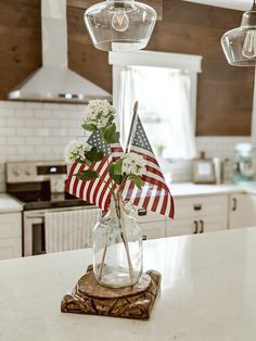 an american flag in a glass vase on a kitchen counter with lights hanging above it