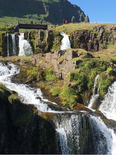 people are standing at the base of a waterfall