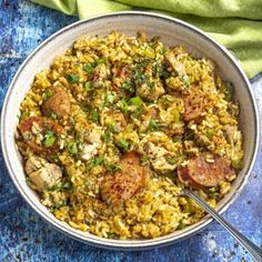 a bowl filled with rice and meat on top of a blue table