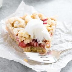 a piece of pie with ice cream on top sitting on wax paper next to a fork