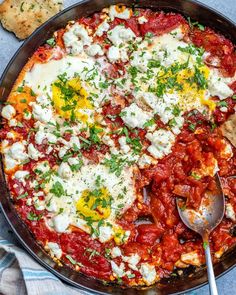 a skillet filled with eggs, tomato sauce and cheese on a blue towel next to crackers