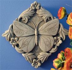 a decorative butterfly on a blue wall next to flowers