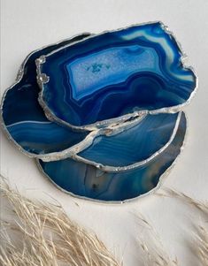 three pieces of blue agate glass sitting on top of each other in front of some dry grass