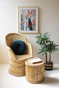 a wicker chair next to a potted plant and a book on a table