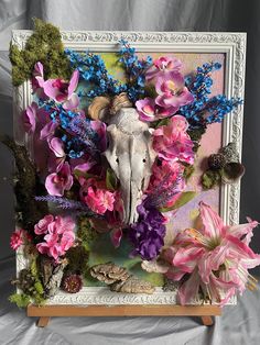 an animal head surrounded by flowers and plants in a white frame on a gray background