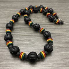 This bold long necklace is made of 20mm black large chunky fluted wooden beads with red, gold, green ceramic rondelle beads and 8mm black lava stone beads. It has a stainless steel lobster claw style clasp with stainless steel wire guards. Available in lengths of 28 and 30 inches. Prices vary. Wooden Beads Necklace, Beaded Necklace Men, Rasta Flag, Jamaican Colors, Wood Beads Jewelry, Bead Accessories, Large Bead Necklace, Poly Clay, Fredericksburg Va