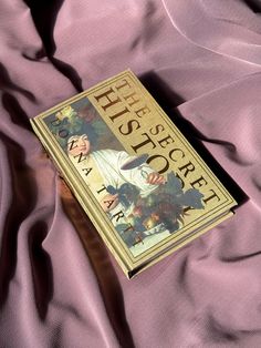 a book sitting on top of a bed covered in pink sheets and purple sheetspread