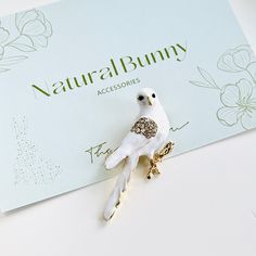 a white bird brooch sitting on top of a card