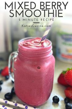 a smoothie in a mason jar with strawberries and blueberries on the side