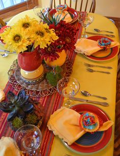 the table is set with plates, silverware and flowers