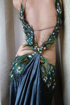 the back of a woman's dress with peacock feathers and beads on it,