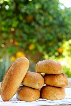 a stack of bread rolls sitting on top of a white towel next to a green tree