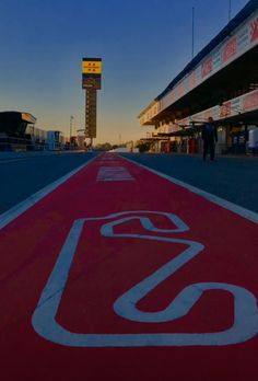 an empty race track with the sun setting in the background